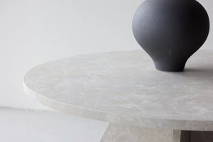 Table basse ronde Bootcut beige utilisée comme table basse de salon